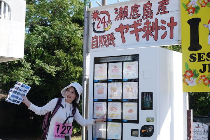 ヤギ汁の自動販売機前で撮影する参加者