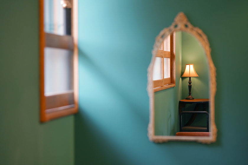 グリーンの壁に飾られた鏡