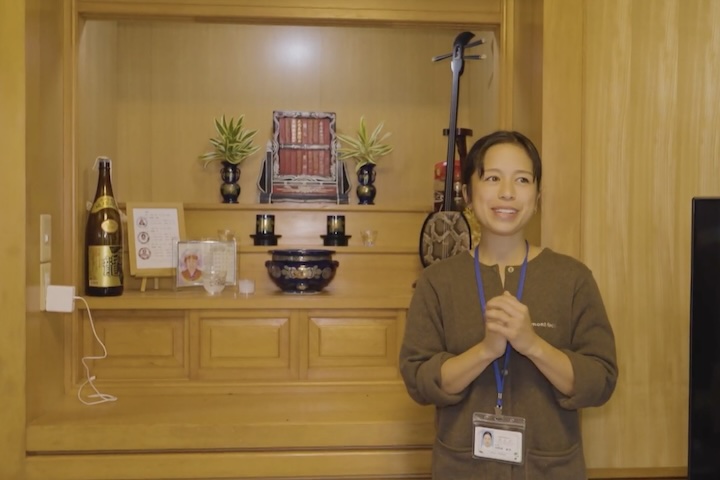 沖縄の仏壇の前に立つ女性