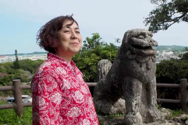 沖縄県内で最大・最古といわれる石獅子（シーサー）と並ぶ女性